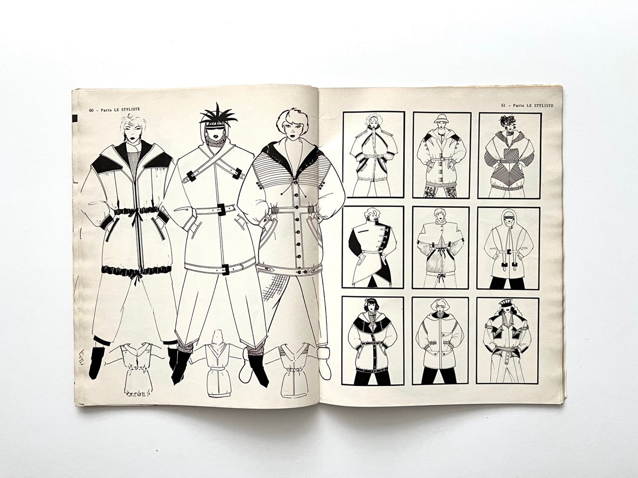 Spread from Paris Le Styliste No. 15 (1985) showing three full-length belted coats with oversized collars, quilted details and contrast panels on the left page; right page presents a 3×3 grid of additional outerwear sketches with varied shapes and textures.