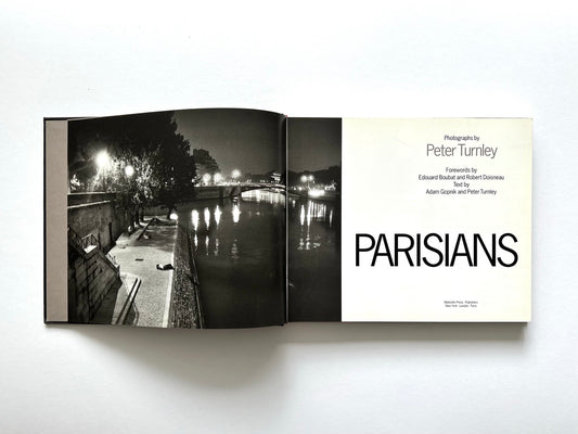 Title page of Parisians by Peter Turnley, published in 2000, showing the book's title and credits opposite a full-page black-and-white night photograph of the River Seine in Paris.