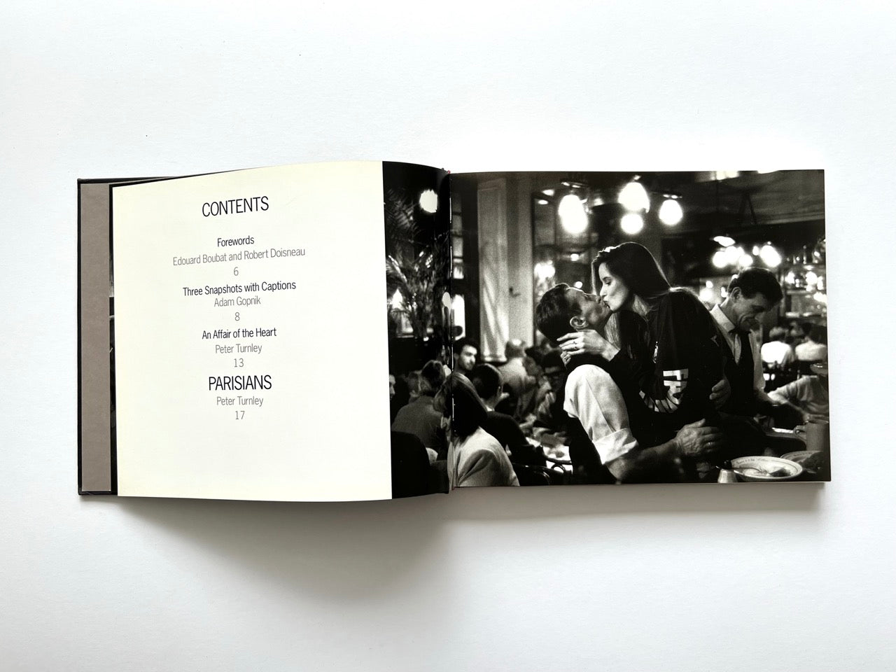 Contents spread from Parisians by Peter Turnley, published in 2000, featuring the table of contents alongside a full-page black-and-white photograph of a couple kissing in a busy Paris café.
