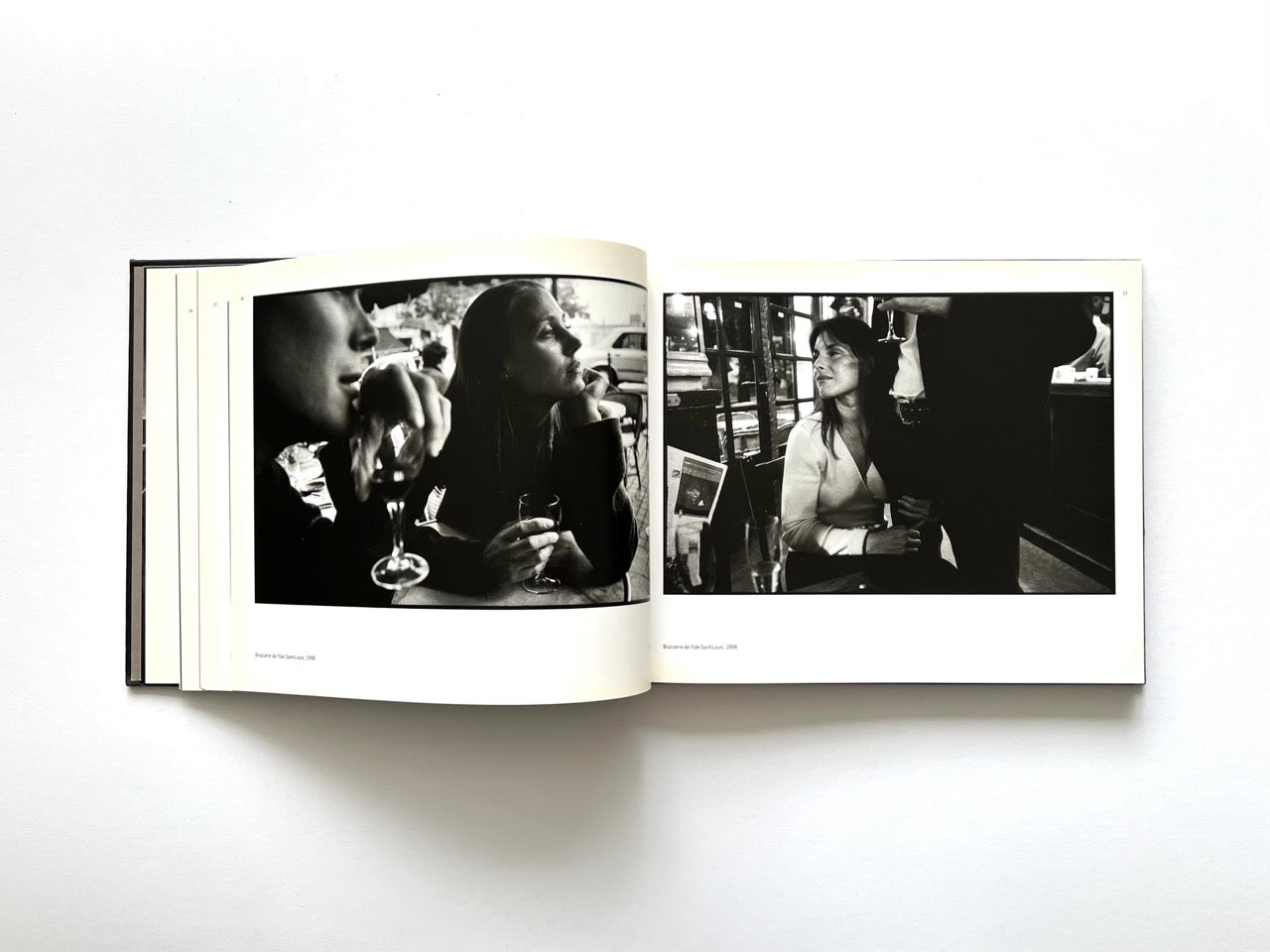 Interior spread from Parisians by Peter Turnley, published in 2000, featuring black-and-white café scenes with people drinking wine and conversing in Paris.