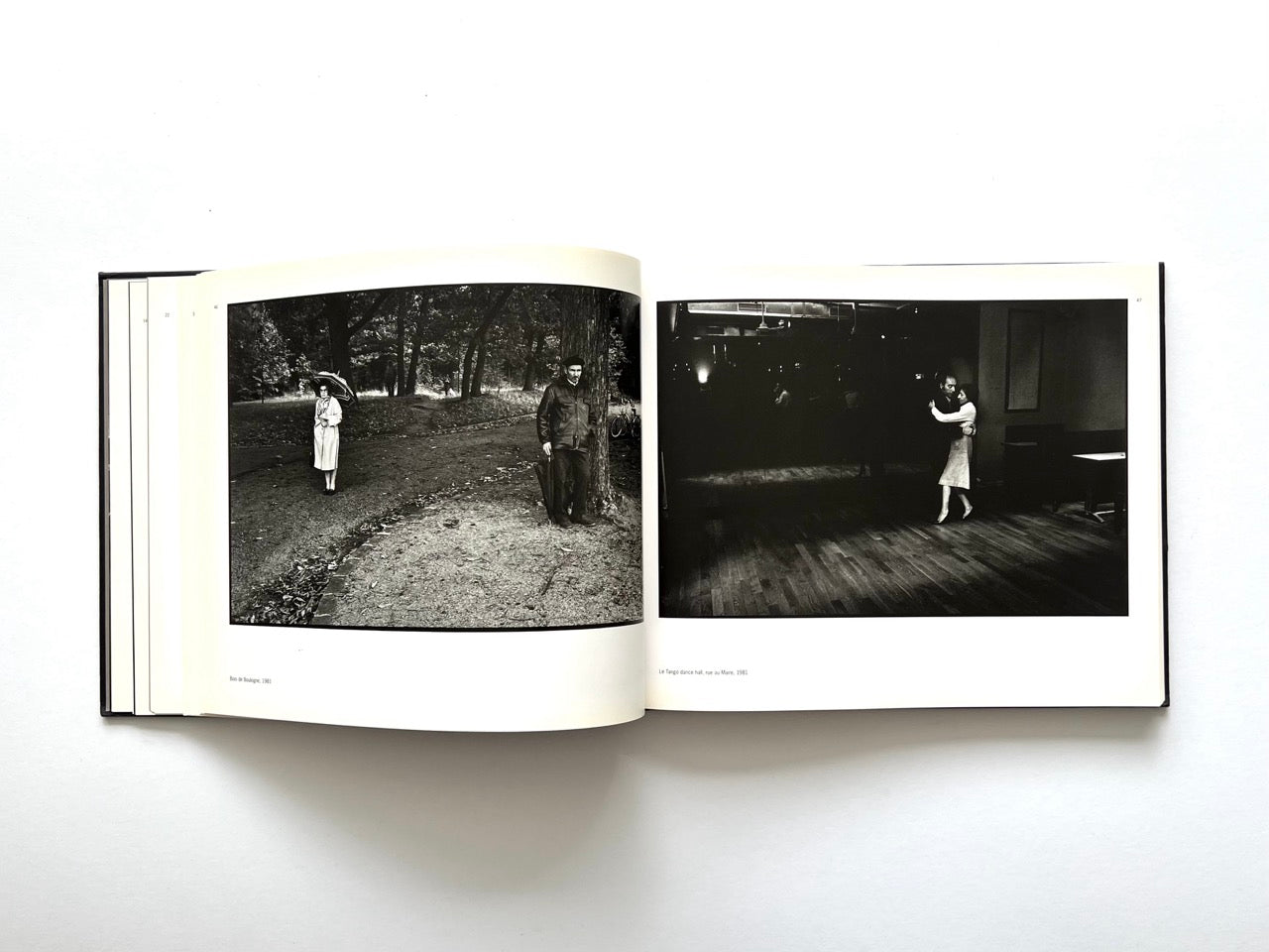 Interior spread from Parisians by Peter Turnley, published in 2000, showing black-and-white photographs of a solitary figure in a park and a couple dancing in a dimly lit hall.