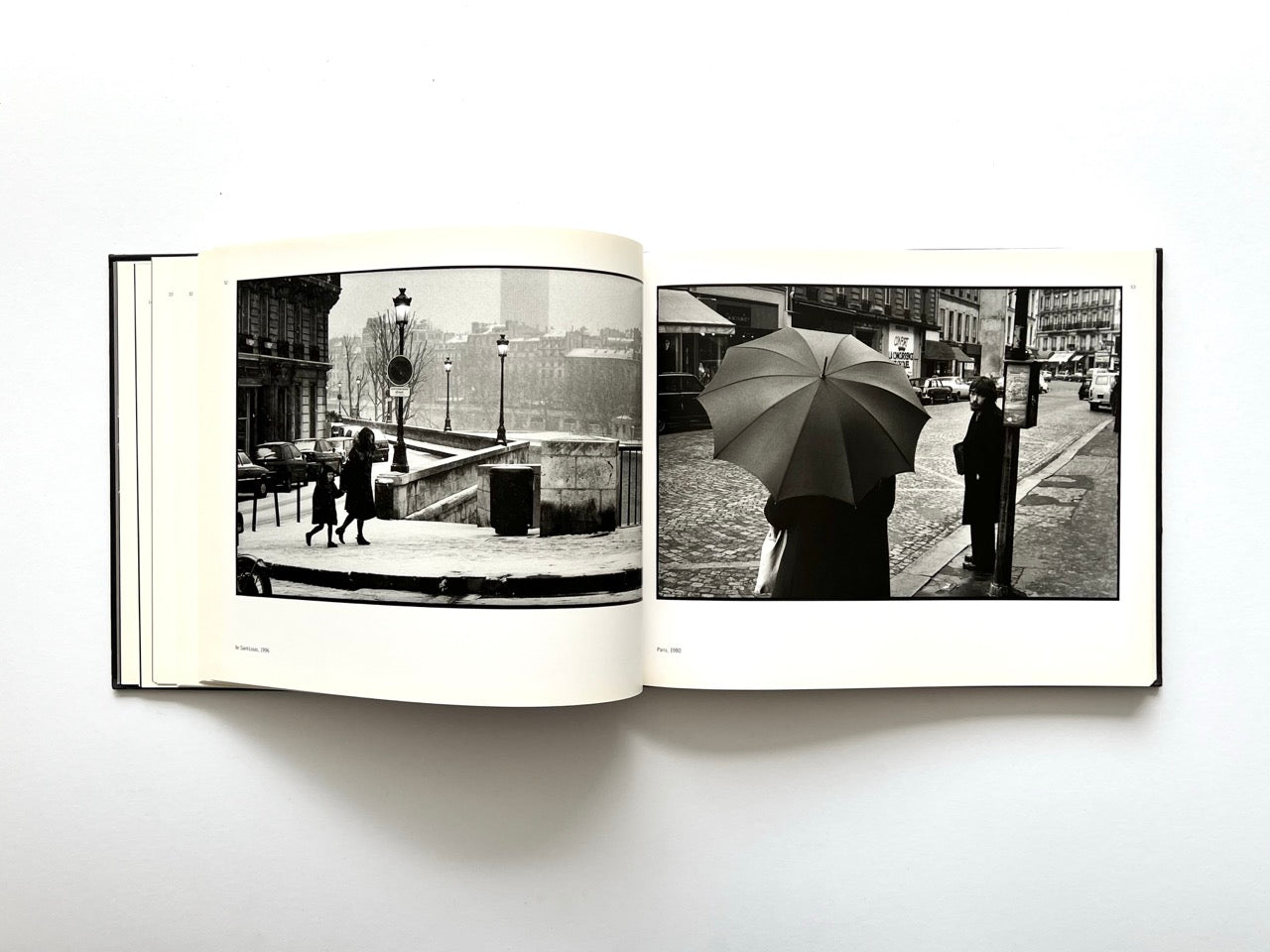 Interior spread from Parisians by Peter Turnley, published in 2000, featuring black-and-white street photographs of rainy Paris scenes with umbrellas and pedestrians.