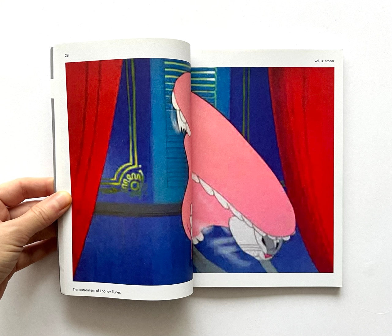 Open book - 'Smear: the surrealism of Looney Tunes vol. 3' - showing a colorful illustration of Bugs Bunny with red curtains on a white background