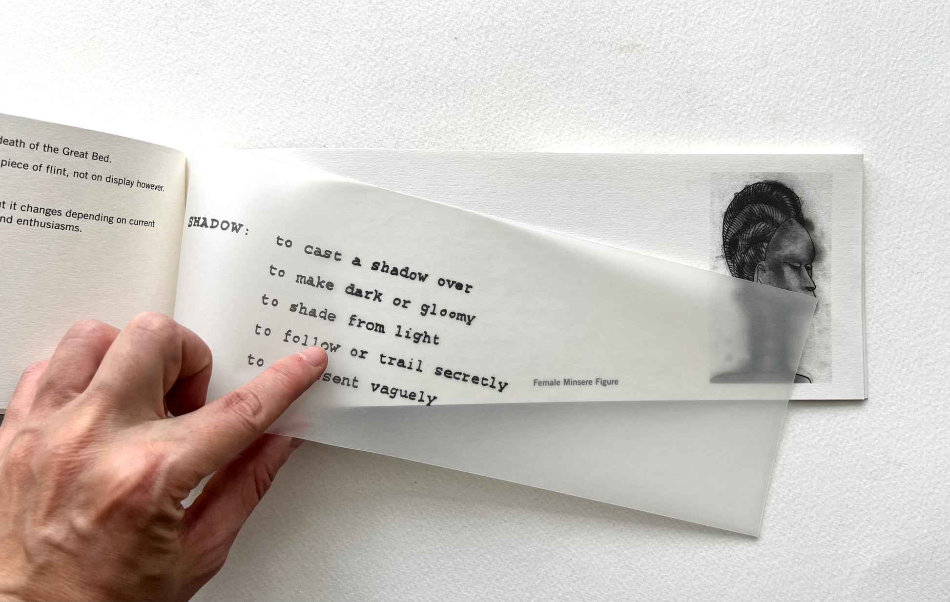 Hand holding a book open to a page with text and an image of a person.
