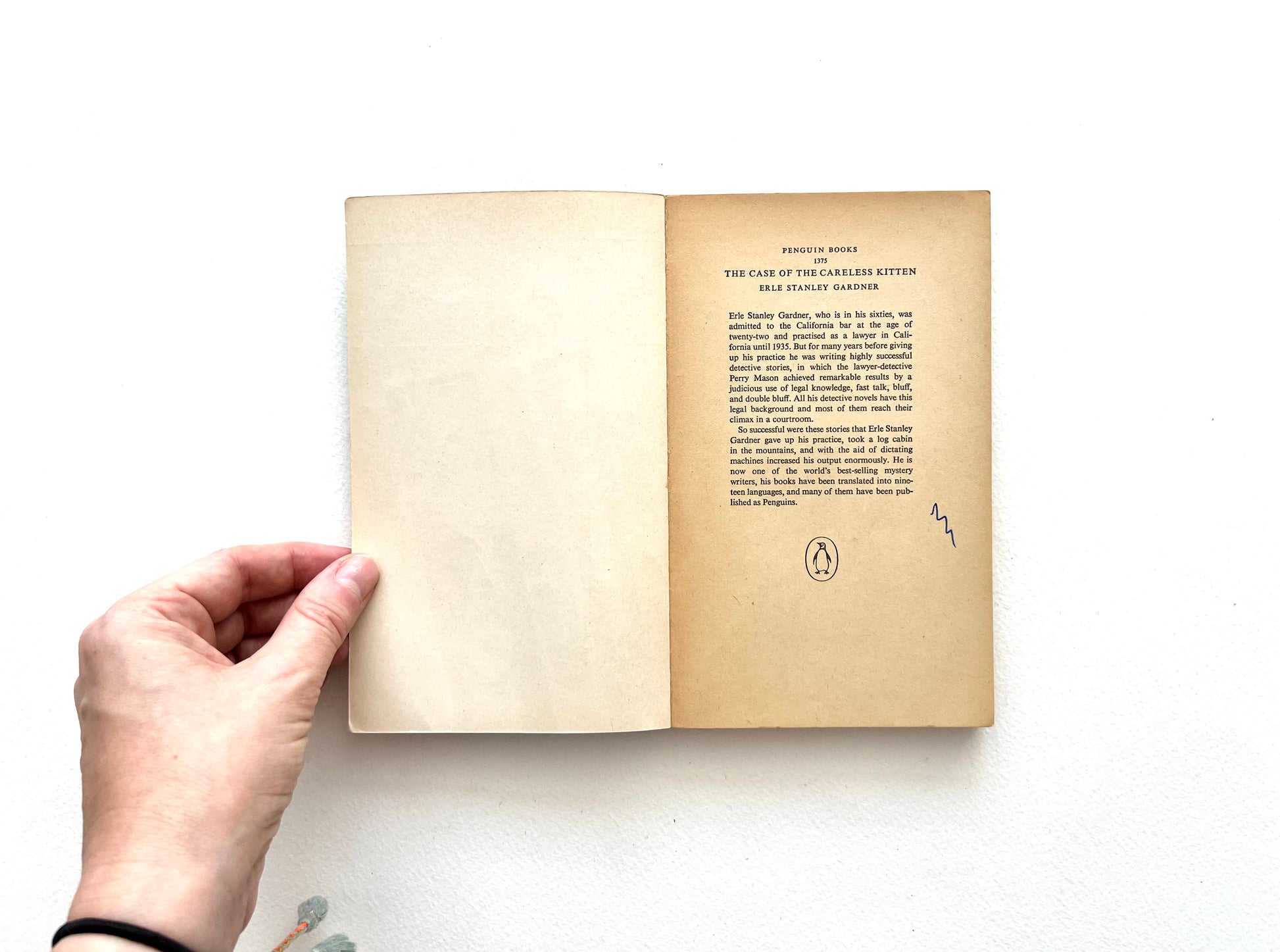 Hand holding an openvintage Penguin paperback book - THE CASE OF THE CARELESS KITTEN - with visible text on a white background