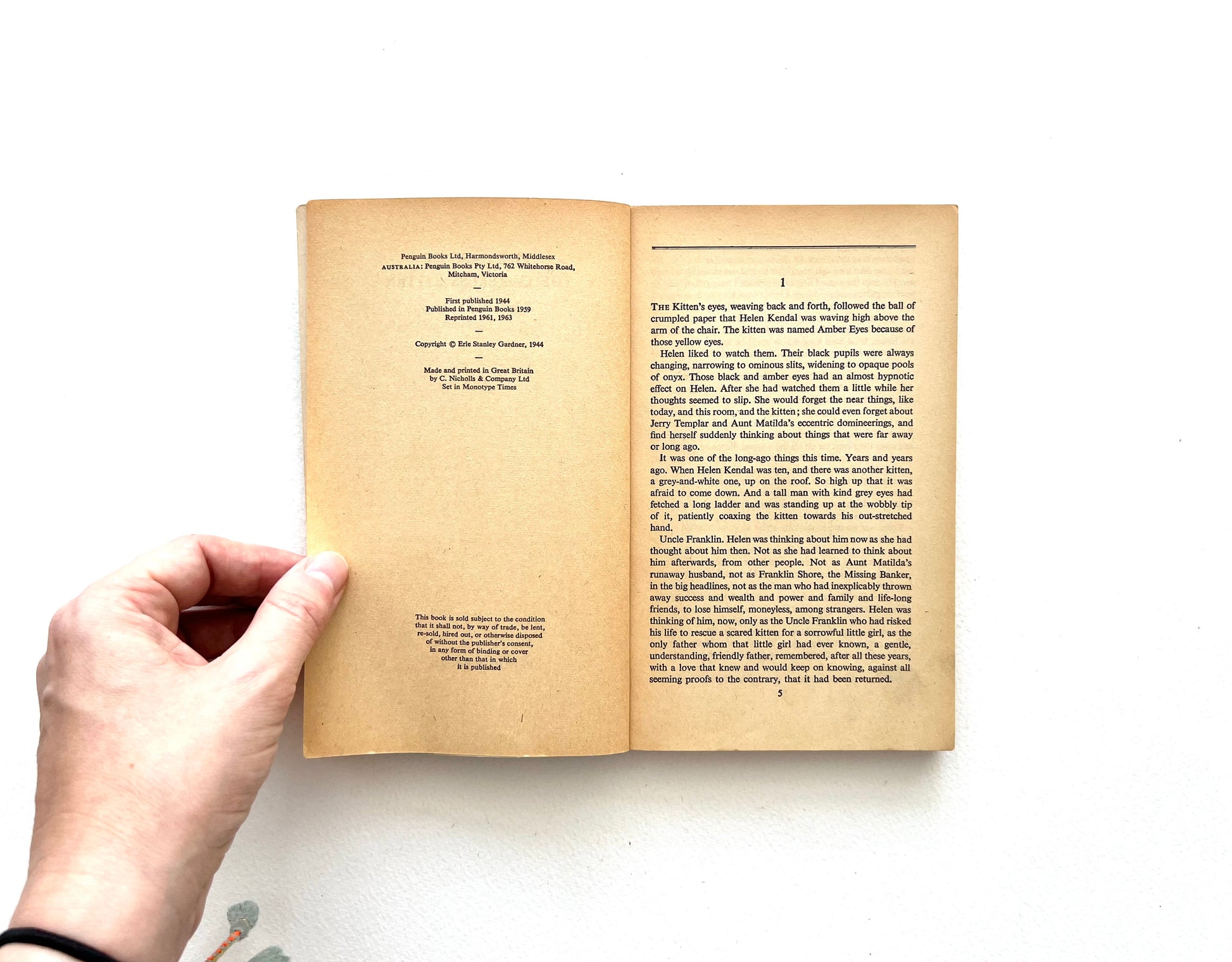 Open vintage Penguin paperback book - THE CASE OF THE CARELESS KITTEN - held by a hand on a white background