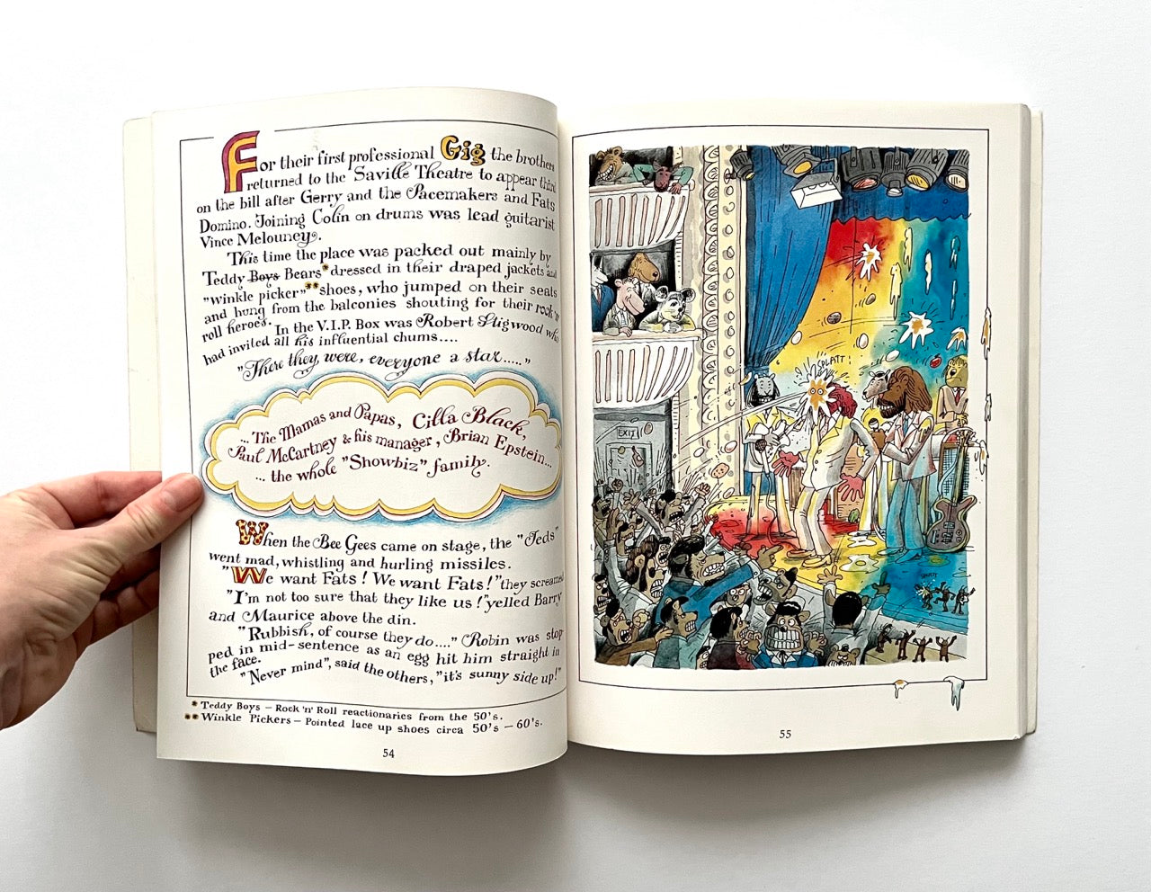 Open book - 'The Legend: The Illustrated Story of the Bee Gees' - with illustration of a band performing on stage.