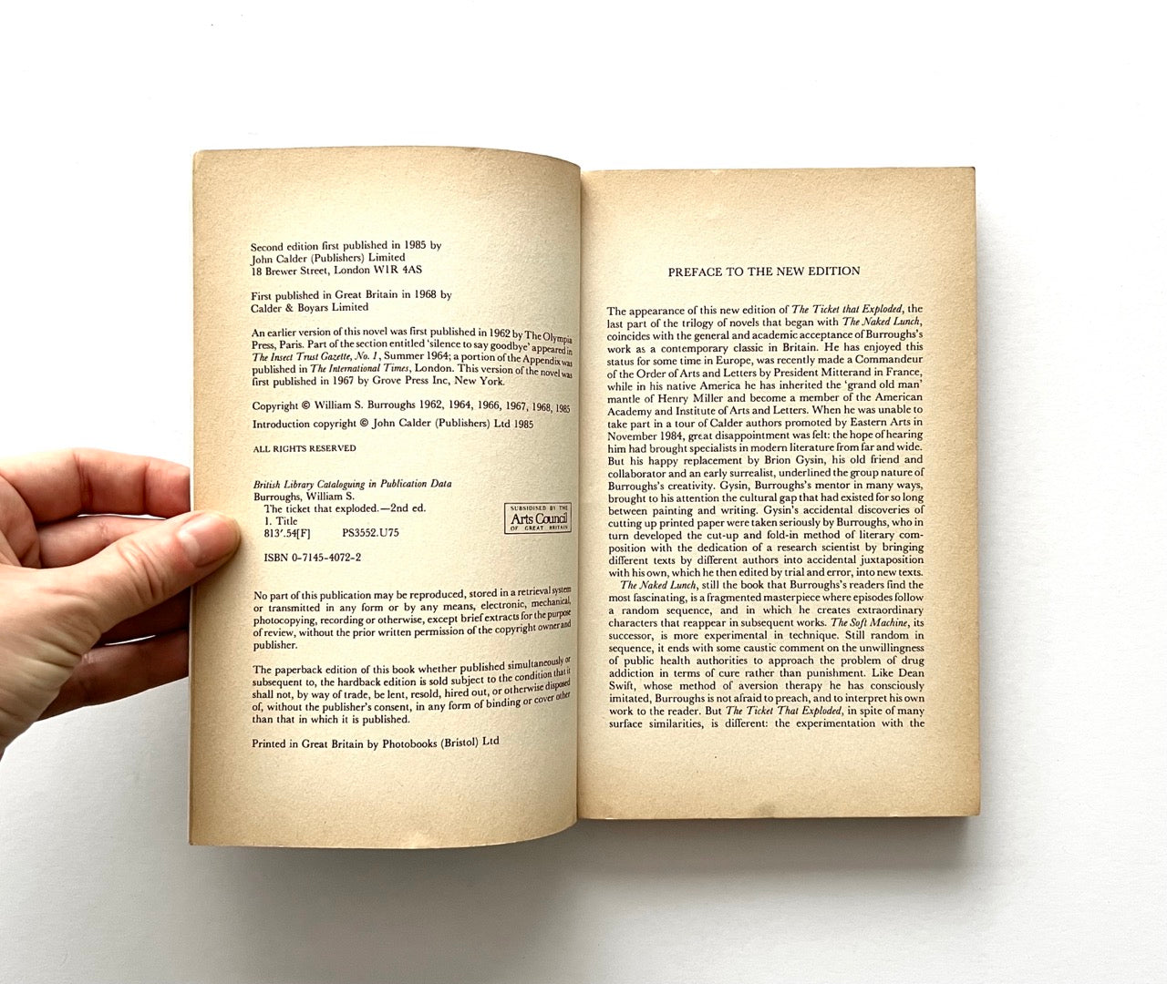 Open book - 'The Ticket That Exploded' by William S. Burroughs - held by a hand.