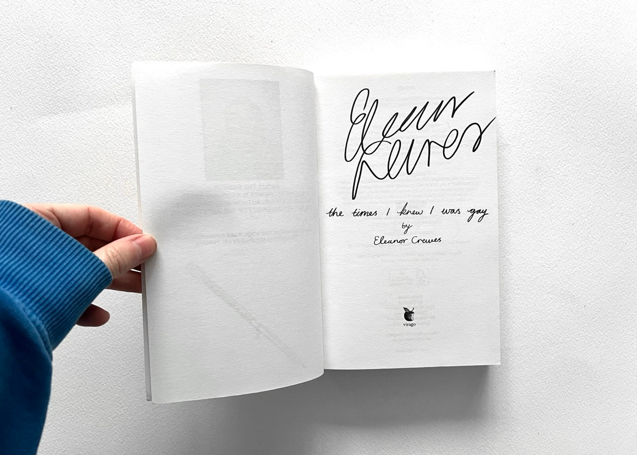 Open book (THE TIMES I KNEW I WAS GAY) showing the title page signed by author Eleanor Crewes.