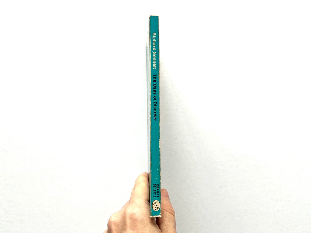Spine of the Pelican paperback edition of The Uses of Disorder by Richard Sennett, showing a turquoise spine with black lettering, Pelican logo at the base, and light edge wear.