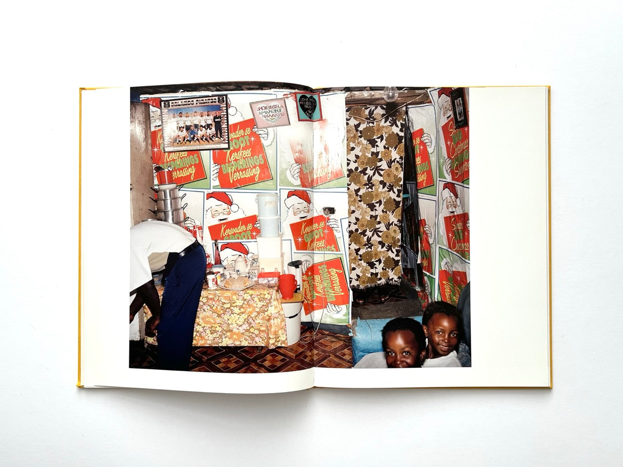 Die Son Sien Alles by Viviane Sassen (2012), interior spread depicting a vibrant domestic space with patterned walls, kitchen items and two children, rich in colour and visual layering.