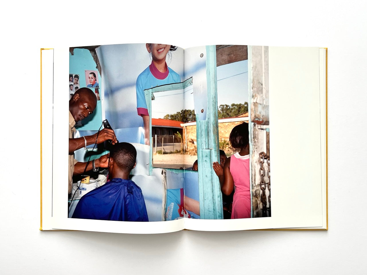 Die Son Sien Alles by Viviane Sassen (2012), interior spread showing a barbershop scene with a haircut in progress, mirrors and posters creating a fragmented visual composition.