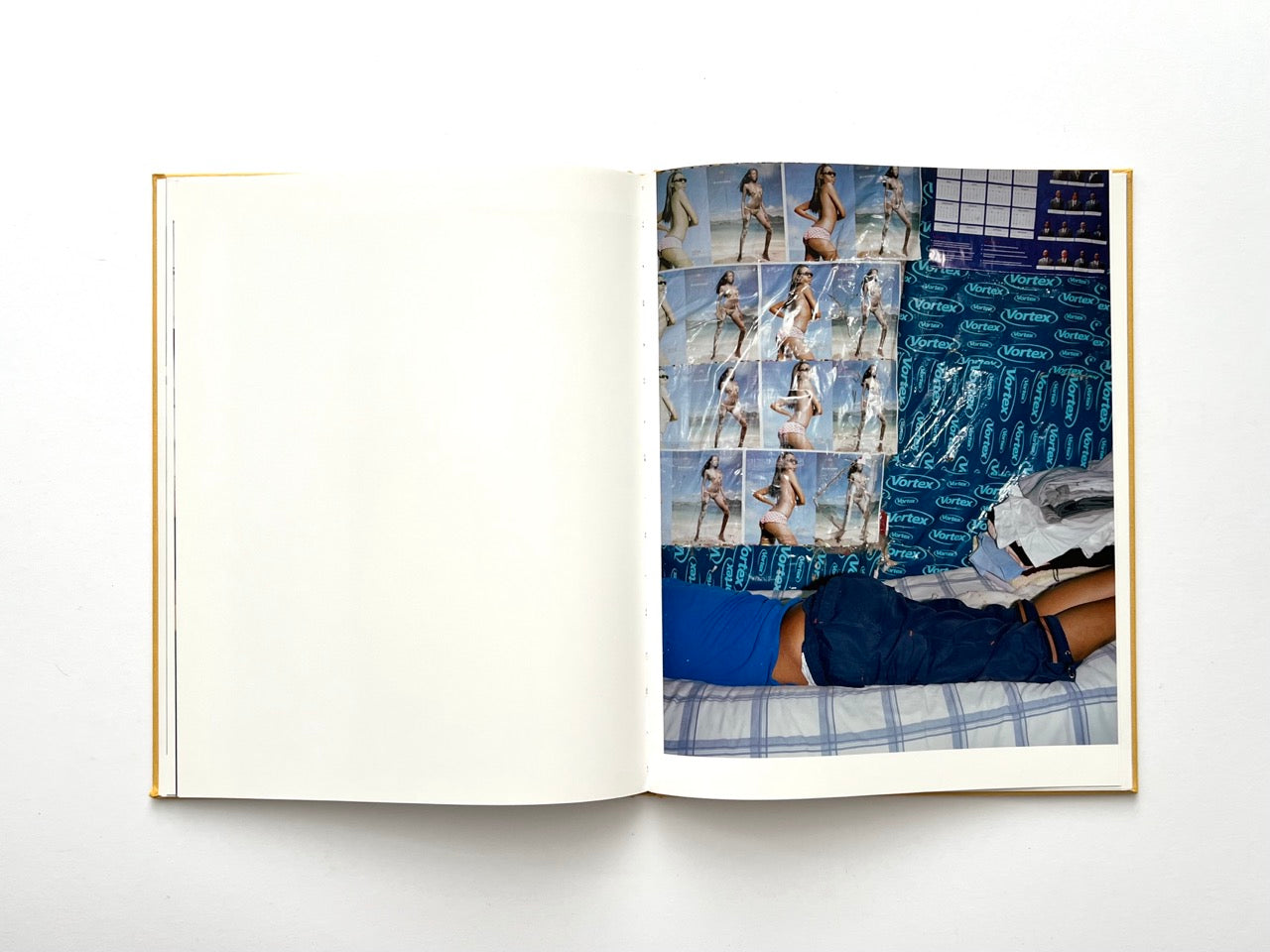 Die Son Sien Alles by Viviane Sassen (2012), interior spread showing a bedroom with blue patterned walls covered in repeated posters of bikini models, a figure lying on a bed partially out of frame, blending intimacy with commercial imagery.