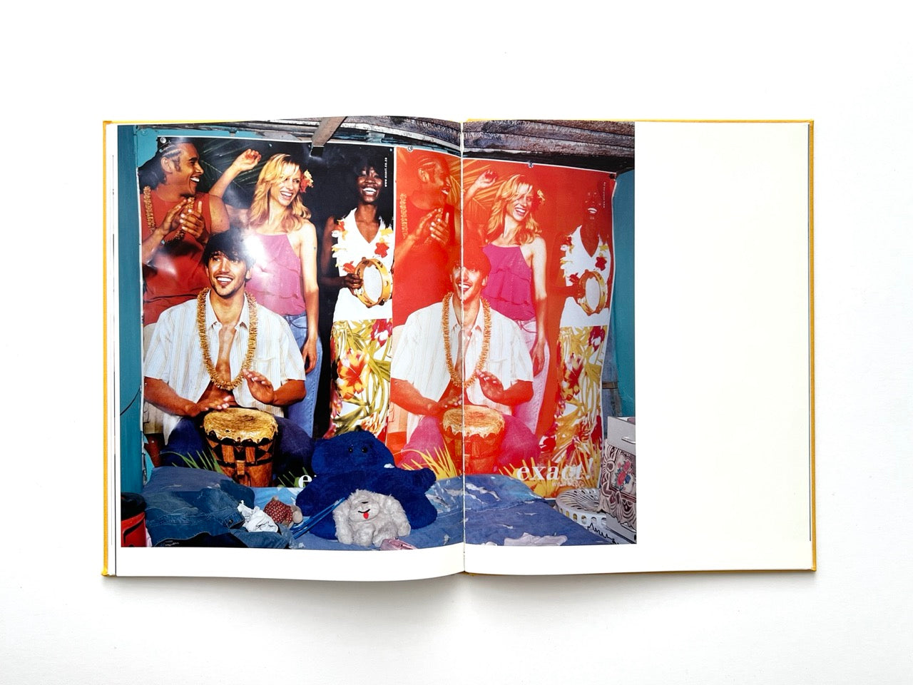 Die Son Sien Alles by Viviane Sassen (2012), interior spread featuring a vivid wall poster of smiling figures playing drums and dancing, set within a modest room with personal belongings in the foreground, creating a contrast between staged joy and lived space.
