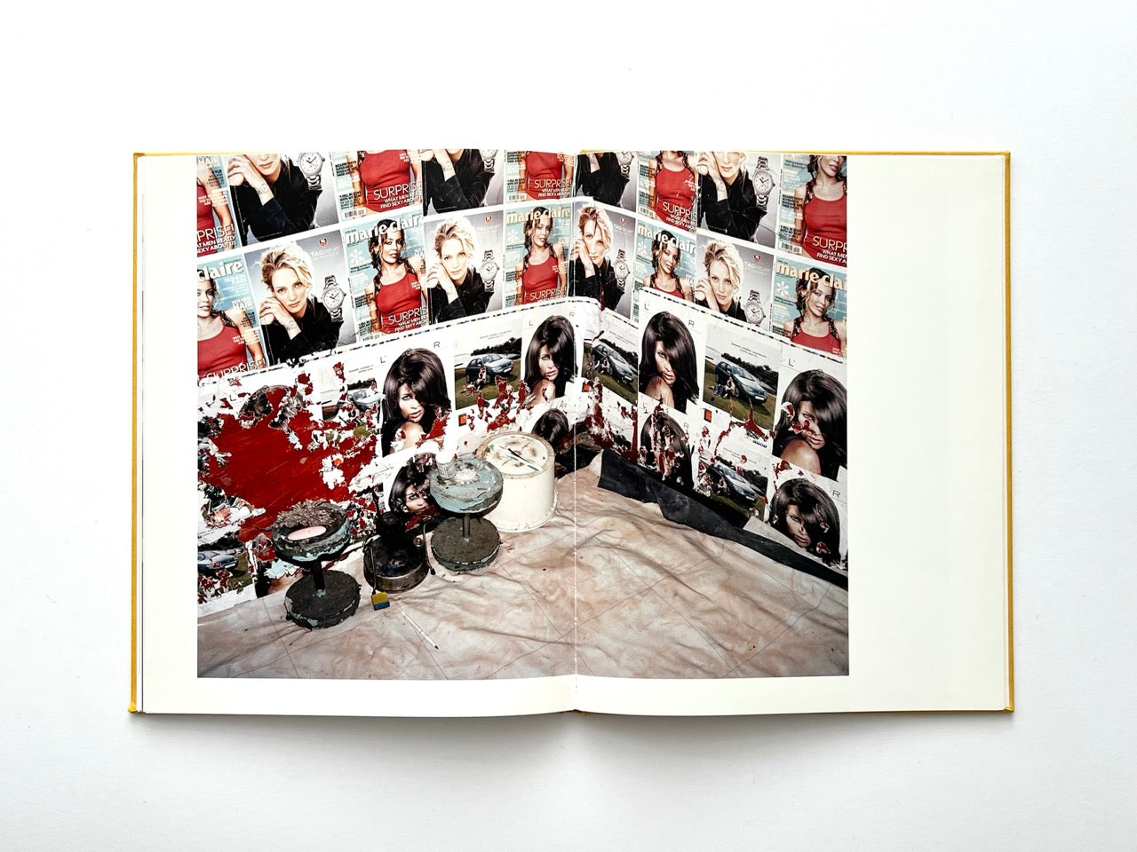 Die Son Sien Alles by Viviane Sassen (2012), interior spread depicting walls covered in layered magazine pages and advertisements, with worn stools and peeling paint in the foreground, highlighting texture, repetition and visual decay.