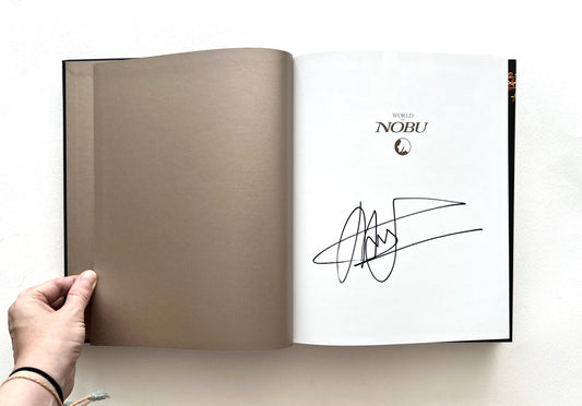 Open 'World of Nobu' book with a signature of Nobu Matsuhisa on a white background.