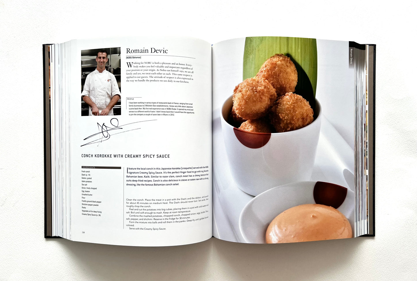 Open "World of Nobu" cookbook showing a recipe and a photograph of CONCH KOROKKE WITH CREAMY SPICY SAUCE dish - signed by chef Romain Devic.