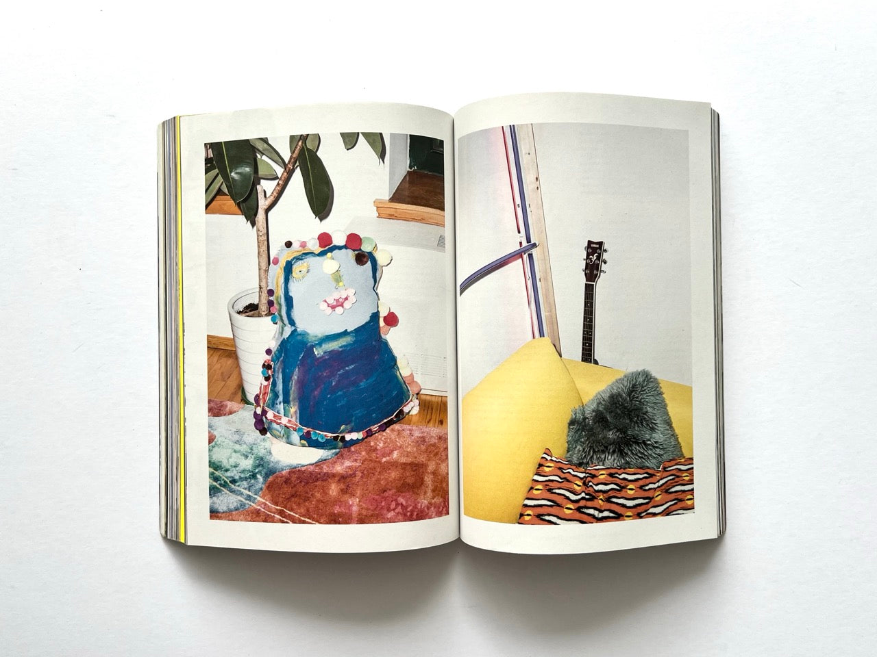Apartamento Magazine Issue #21 – Interior spread with playful home objects, including a painted sculptural piece beside a plant and a guitar leaning against a wall.