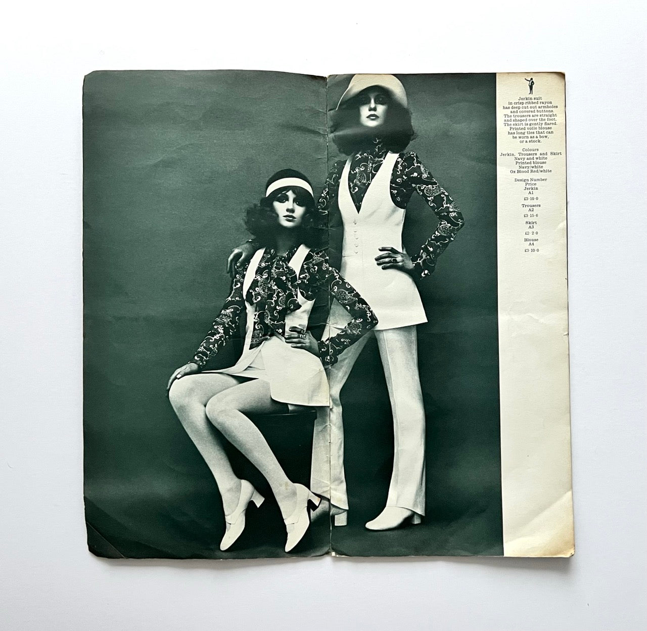 Biba catalogue spread showing two models in matching jerkin, blouse and trousers set, black and white studio fashion photograph with price list column on the side