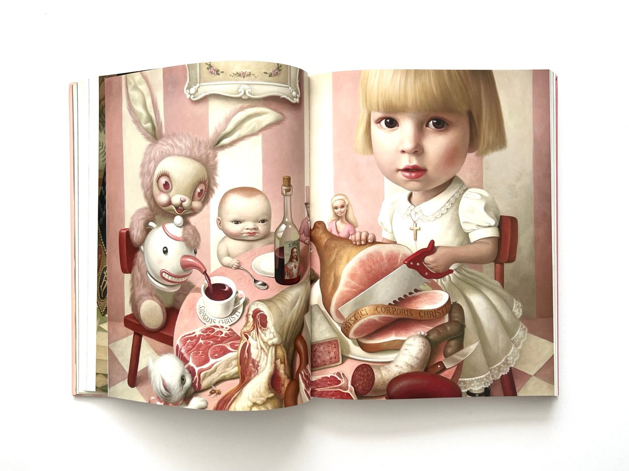 Mark Ryden Pinxit interior spread showing a surreal dinner scene with a child cutting meat, a rabbit figure, and symbolic food elements on a pink striped background