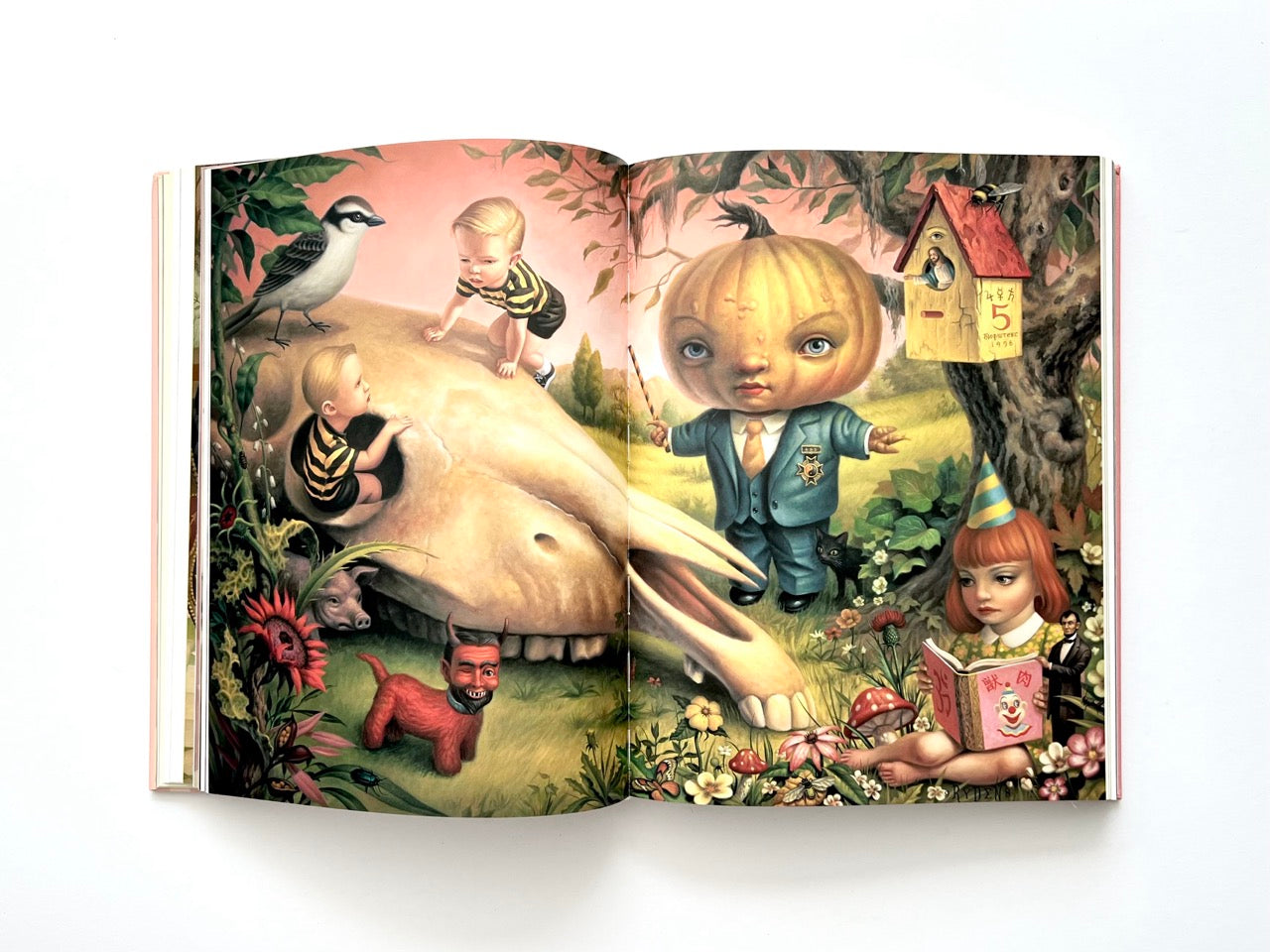 Mark Ryden Pinxit interior spread showing a detailed surreal landscape with children, animals, a large skull-like form, and whimsical figures including a pumpkin-headed character