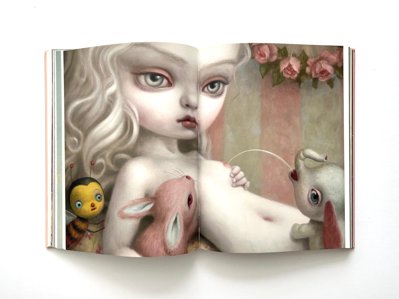 Mark Ryden Pinxit interior spread showing a pale childlike figure with large eyes surrounded by a bee and rabbit figures in a soft, dreamlike composition