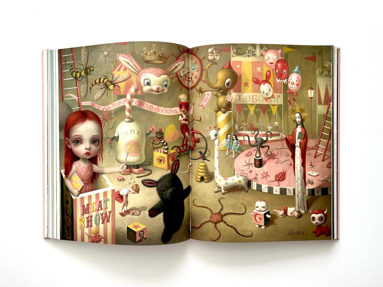 Mark Ryden Pinxit interior spread depicting a dense surreal carnival-like scene with children, animals, bees, religious symbols, and whimsical characters across a detailed stage setting