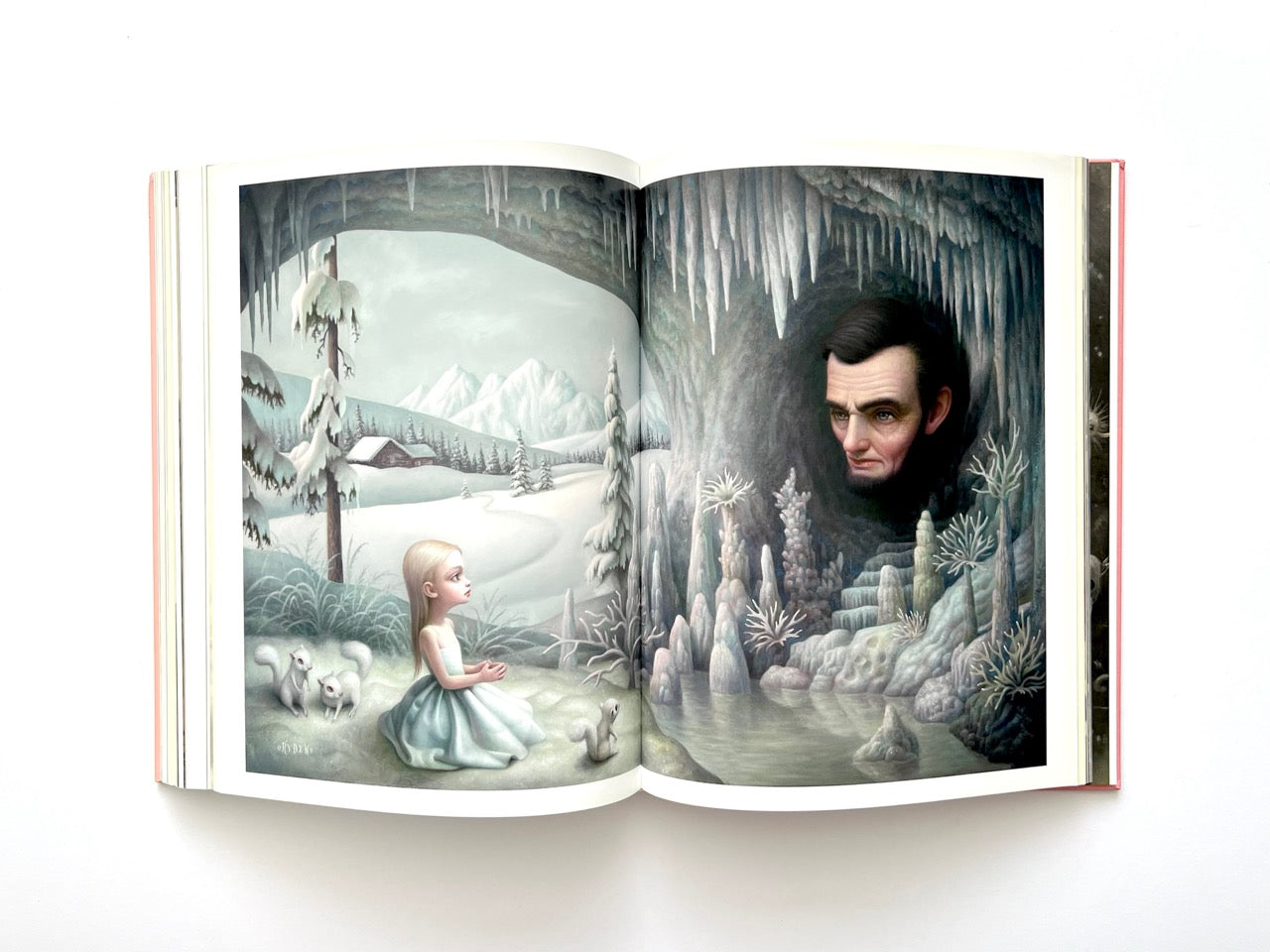 Mark Ryden Pinxit interior spread depicting a young girl kneeling in a snowy landscape facing a cave formation containing the face of Abraham Lincoln, surrounded by icicles