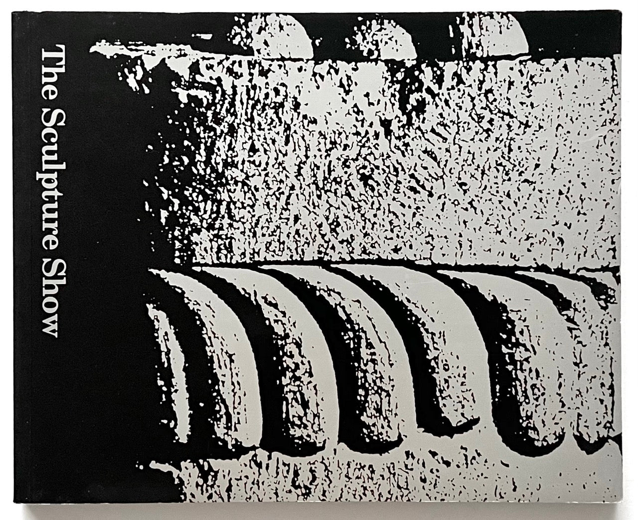 A black-and-silver cover of “The Sculpture Show” (1983) featuring a high-contrast, abstract close-up of carved stone or architectural detail, with the title printed vertically along the left edge.