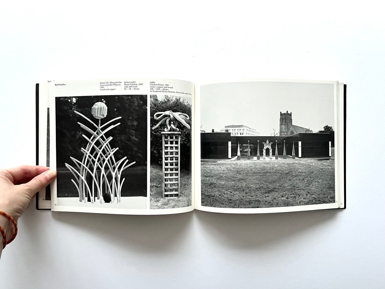 Open spread from “The Sculpture Show” (1983) featuring black-and-white photographs of tall sculptural forms in outdoor settings, including organic lattice-like structures and a row of vertical elements installed in a public space with buildings in the background.