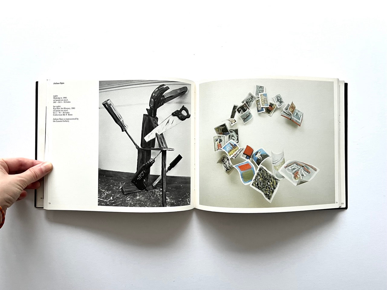 Open spread from “The Sculpture Show” (1983) featuring a black-and-white photograph of an assemblage by Julian Opie, made from tools and wooden elements on the left, and a colour photograph on the right showing small folded sculptural forms arranged in a spiral on a light background.