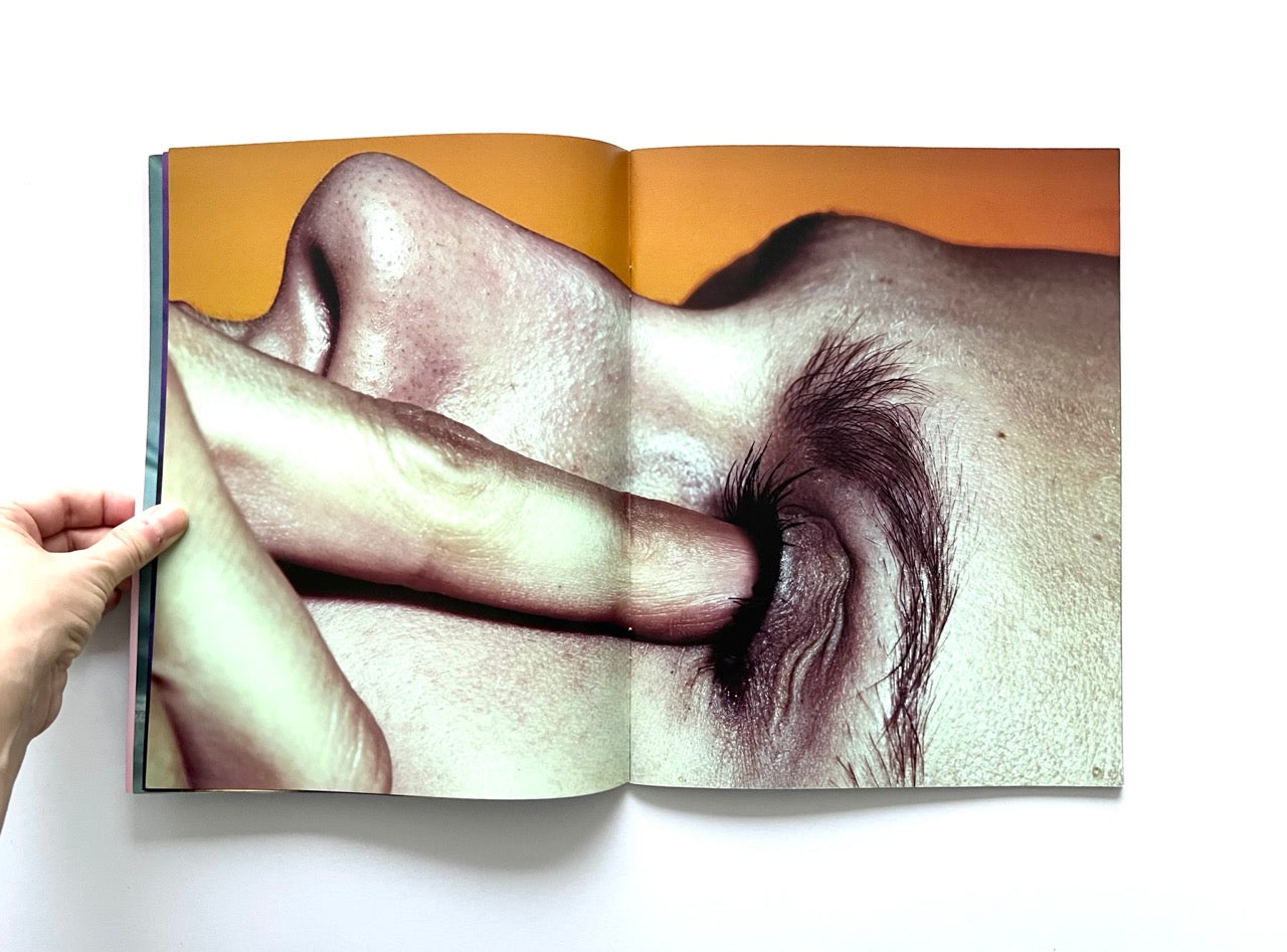 Magazine spread (Toiletpaper No. 7, December 2012) showing a close up of a face with an index finger pushing against the left eye.