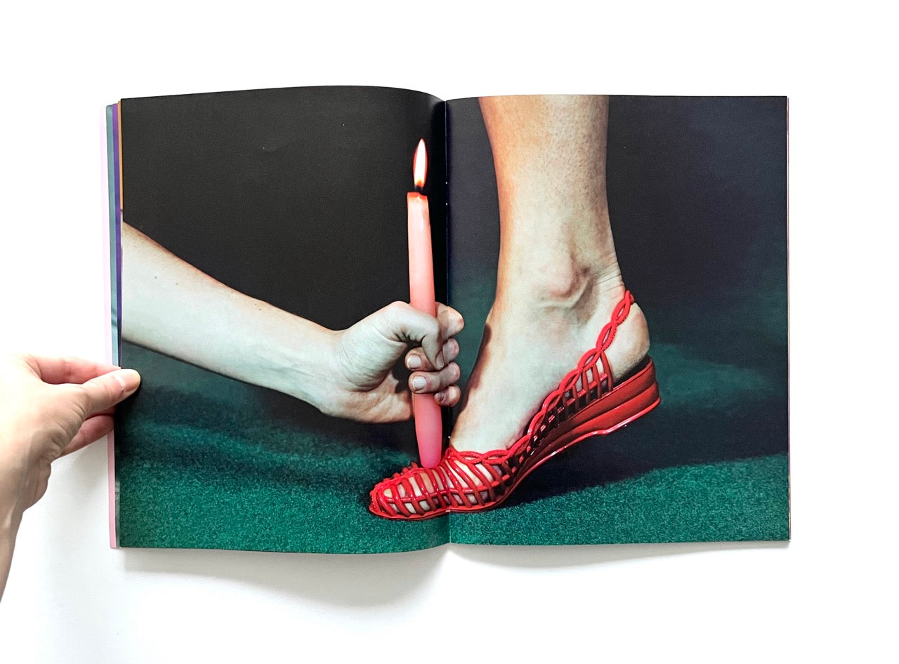 Magazine spread (Toiletpaper No. 7, December 2012) showing female foot in a red braided shoe and a pink candle being placed on top of the foot.